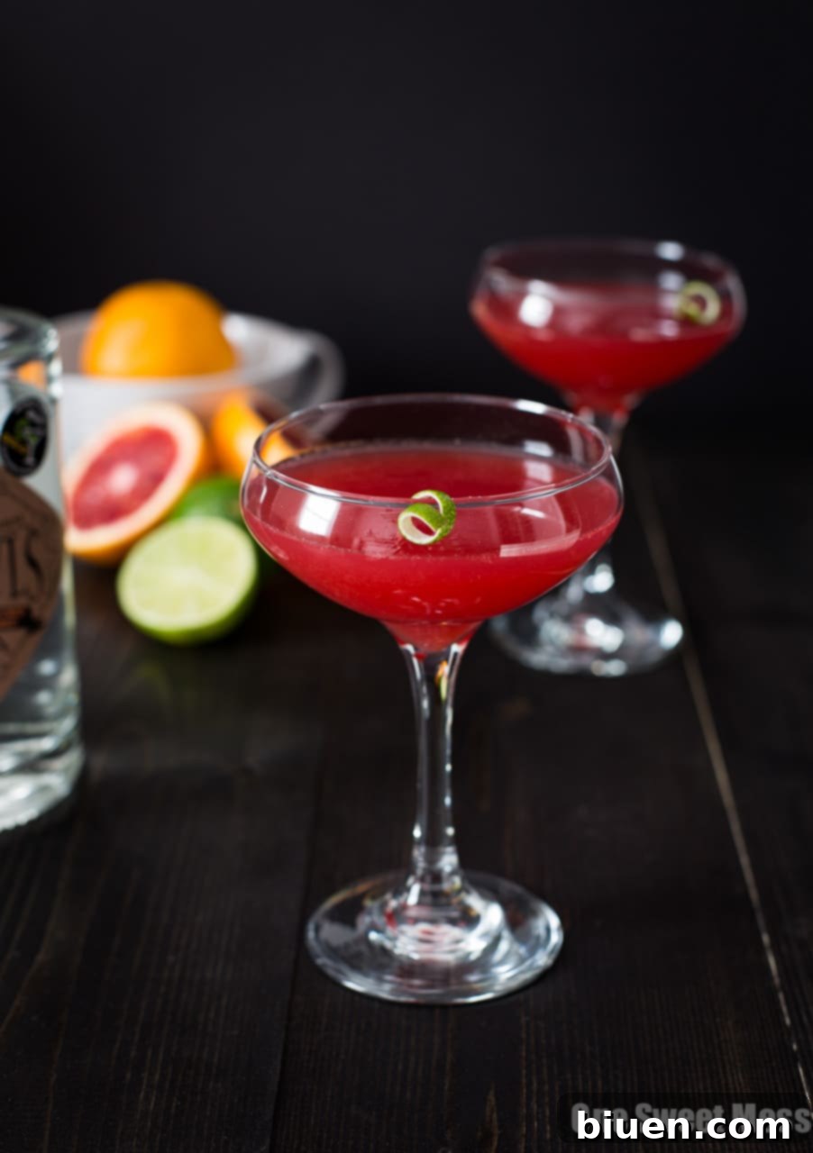Blood Orange Cosmo Cocktail - A vibrant, perfectly pink cocktail in a martini glass, garnished with a lime wedge.