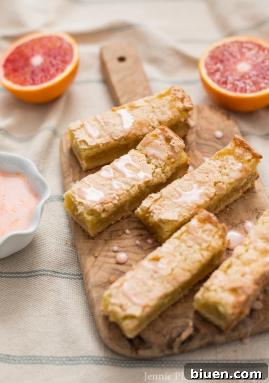 Blood Orange Jewel Bites, Vanilla Cloud Kiss 5 A close-up view of the Blood Orange Bars, showing the vibrant pink glaze glistening over their moist tops
