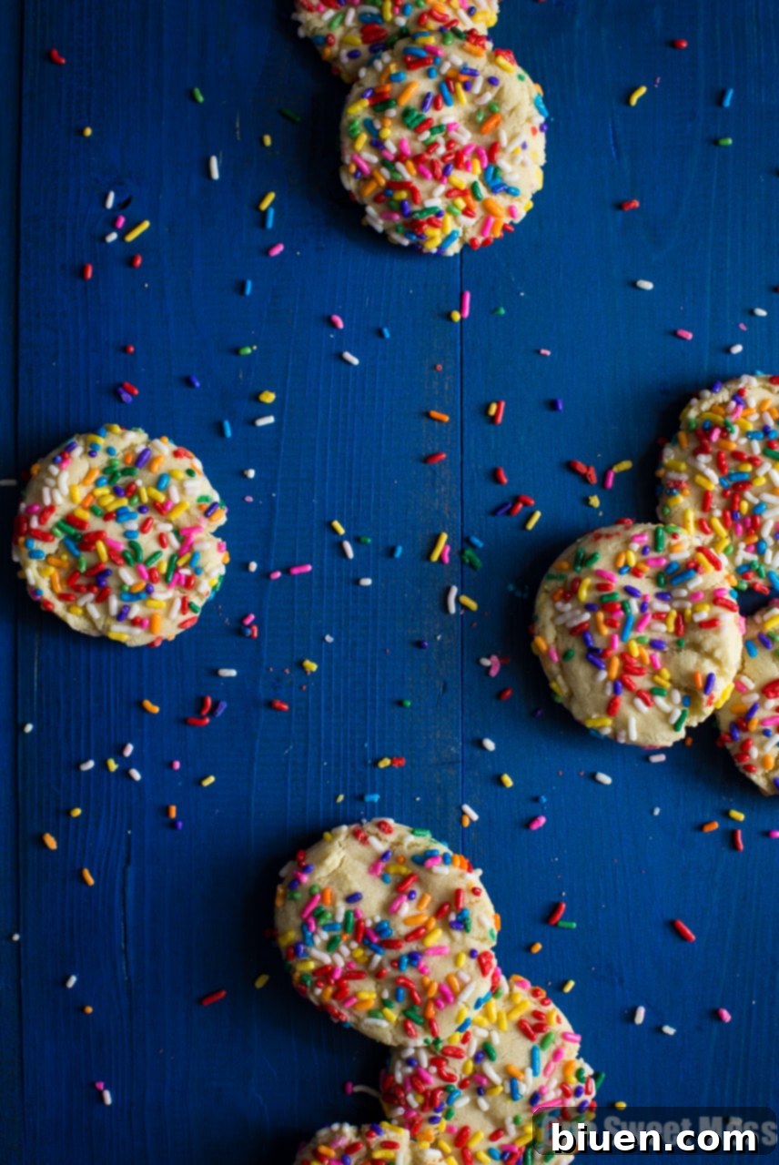 Confetti Cloud Sugar Cookies 3 Close-up of a hand gently holding a soft-baked funfetti sugar cookie, showcasing its texture