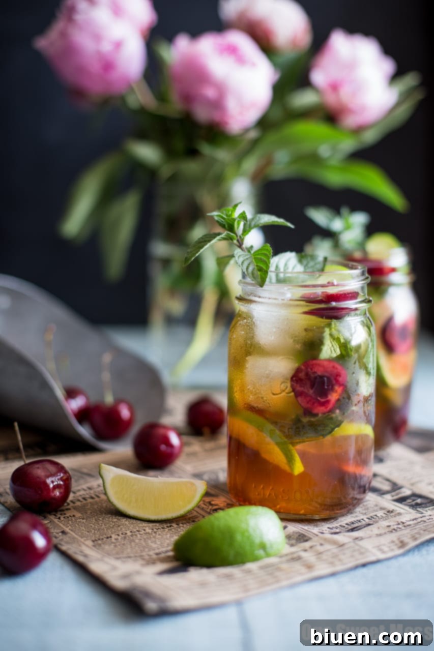 Close-up of a Black Cherry Mule cocktail in a mason jar, showcasing the vibrant colors and fresh ingredients.
