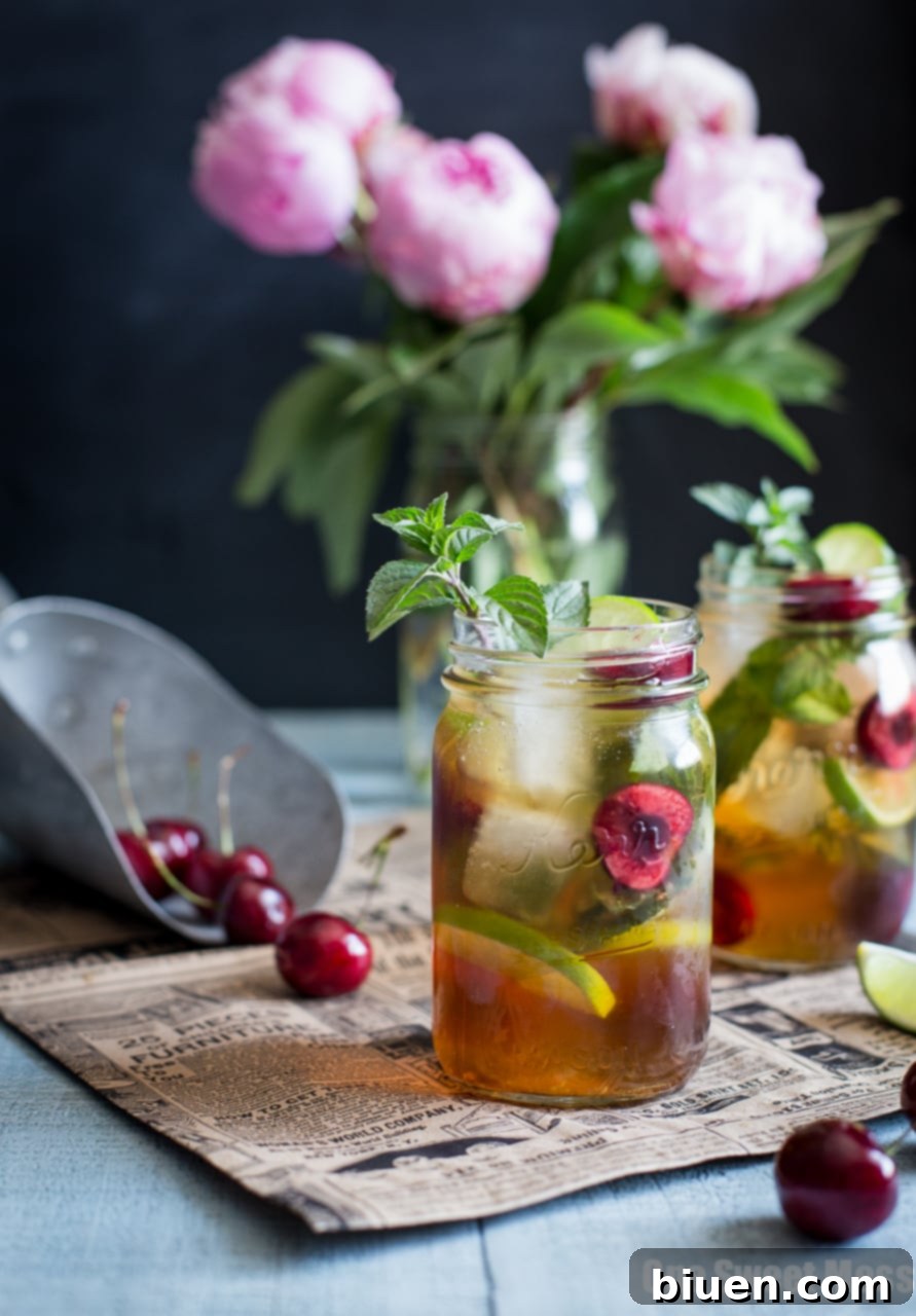 Ingredients for Black Cherry Mule: fresh cherries, lime, mint, simple syrup, and cherry whiskey on a rustic wooden surface.
