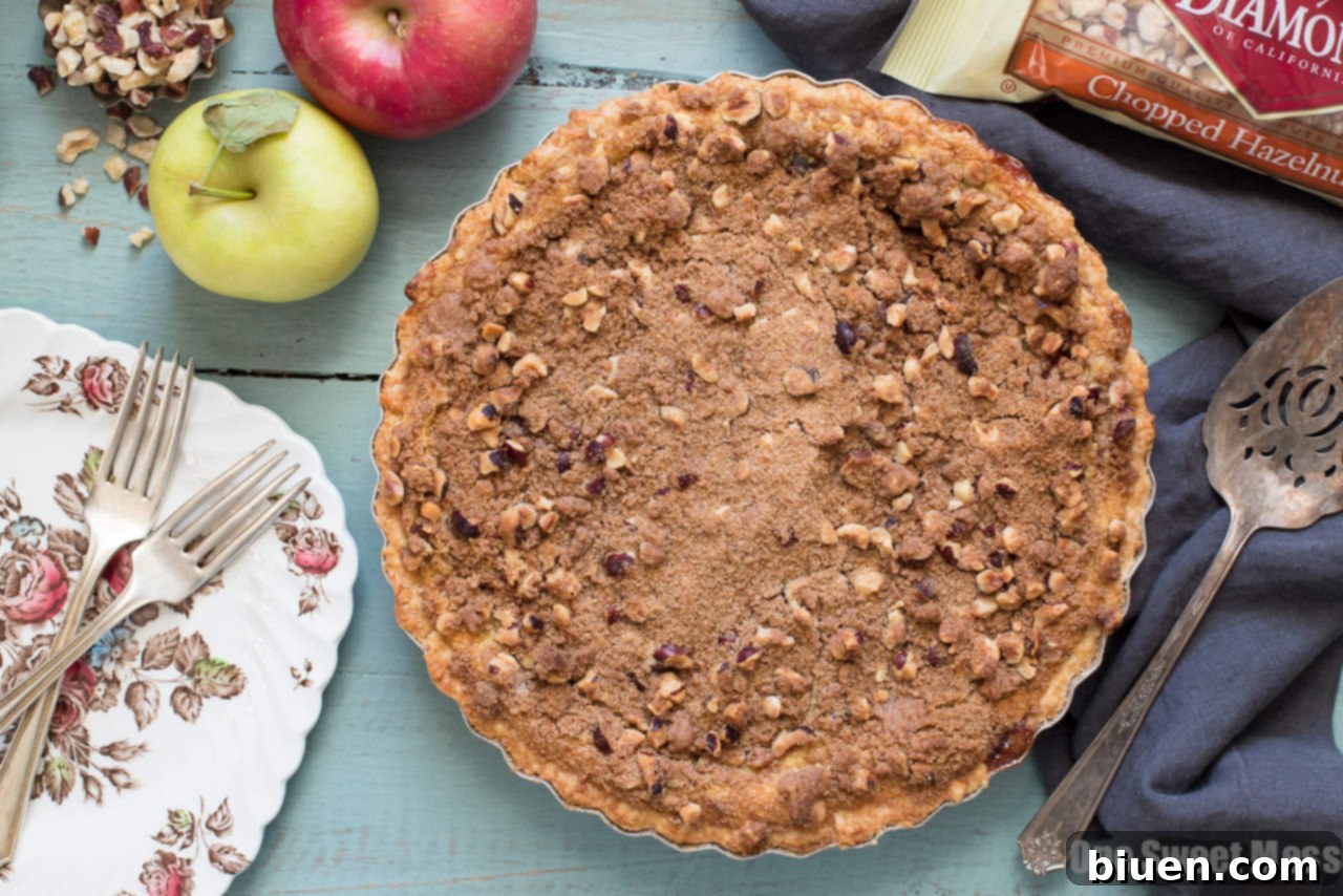 Rich Apple Custard Pie topped with Hazelnut Streusel and Whiskey Cinnamon Whipped Cream, perfect for holidays.