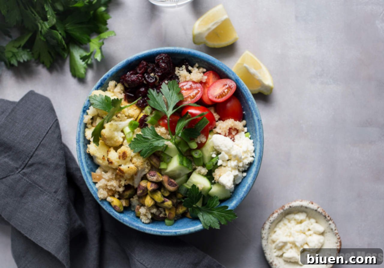 Overhead shot of a large bowl of Roasted Cauliflower Quinoa Salad with Lemon Tahini Dressing, beautifully showcasing all colorful ingredients