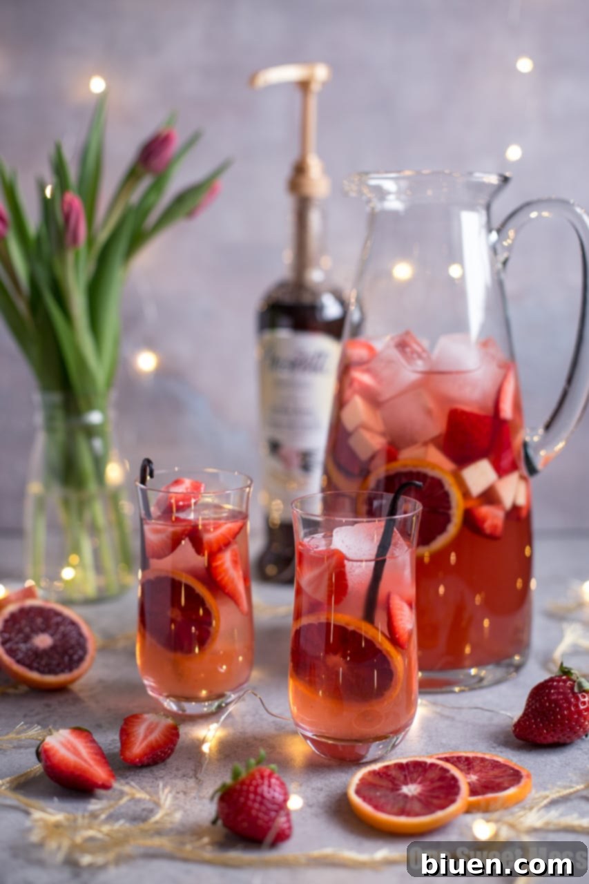 Blood Orange Vanilla Bean Rosé Sangria in a glass pitcher, garnished with fresh fruit