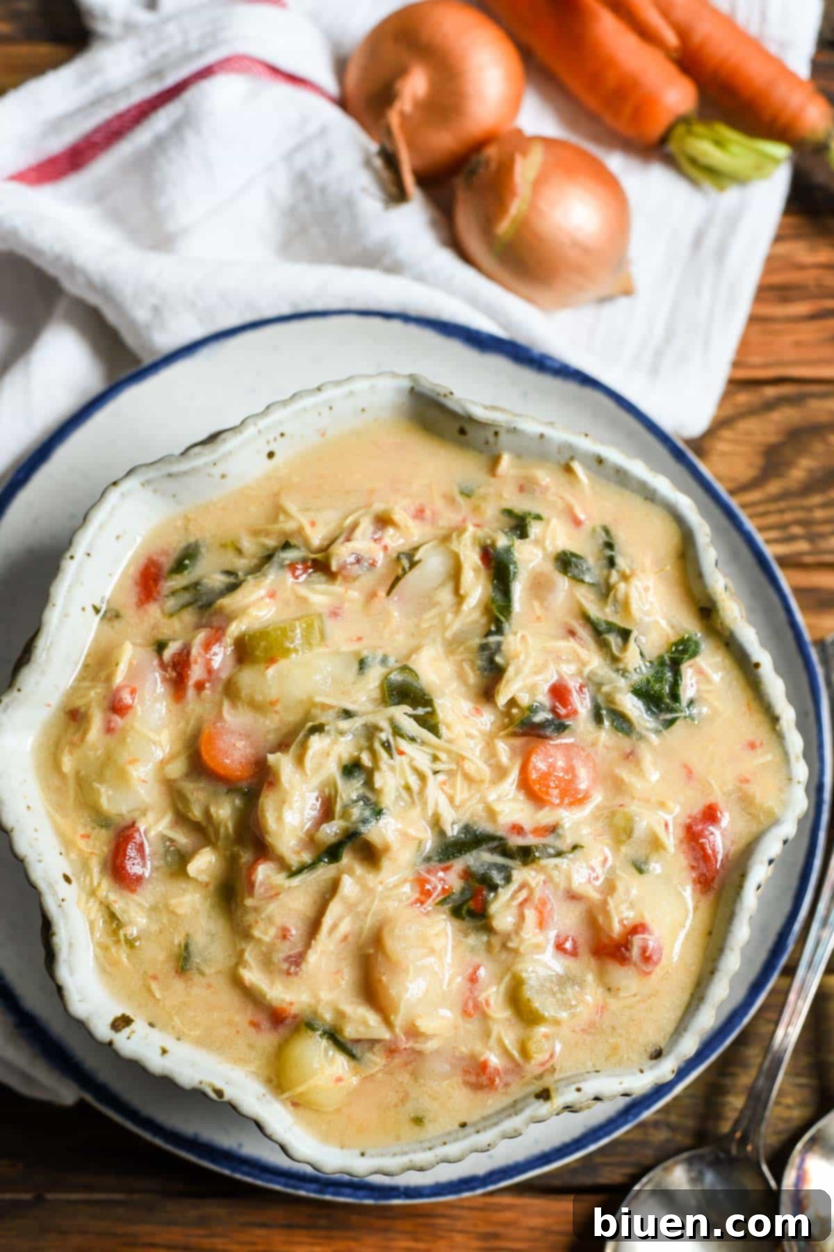 A bowl of creamy Crockpot Chicken Gnocchi Soup, garnished with fresh herbs and served with crusty bread.