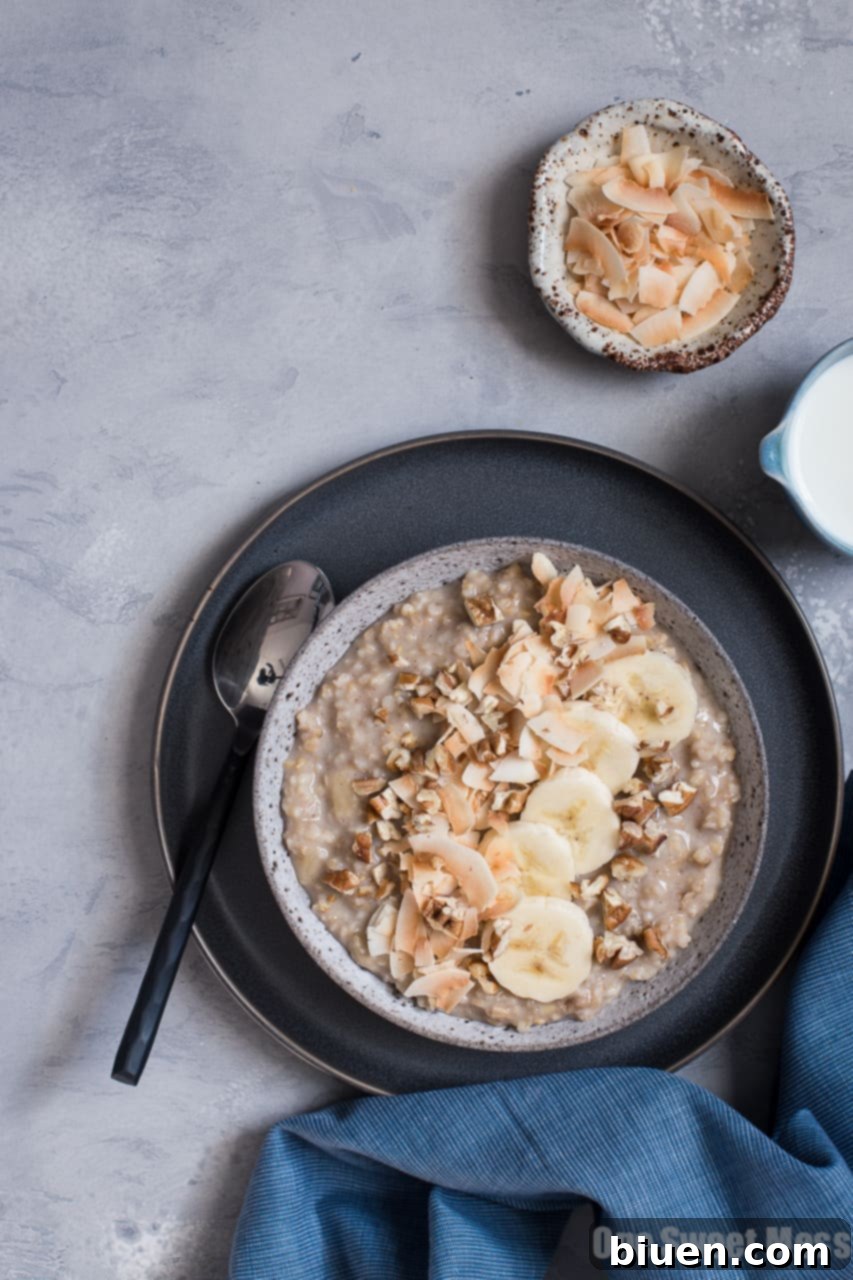 Overhead shot of Banana Bread Steel Cut Oatmeal, elegantly arranged with toasted coconut flakes, pecan halves, and fresh banana slices, ready to be enjoyed.