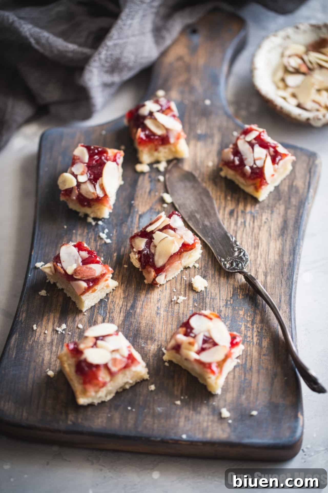 Close-up of a Gluten-Free Cherry Almond Shortbread Bar, showing layers of shortbread, cherry jam, and sliced almonds