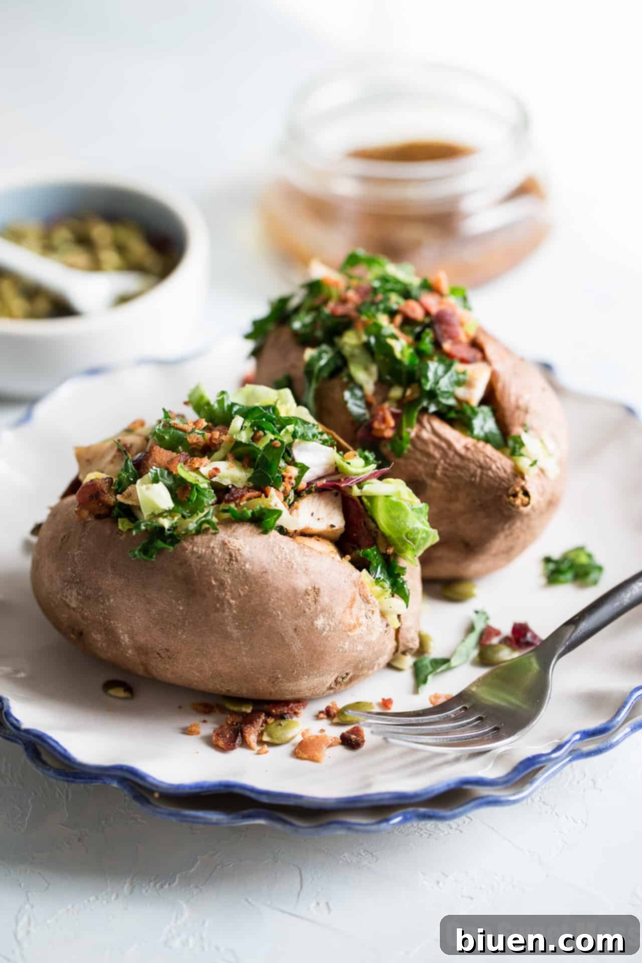 Assembling a stuffed sweet potato with kale salad and grilled chicken
