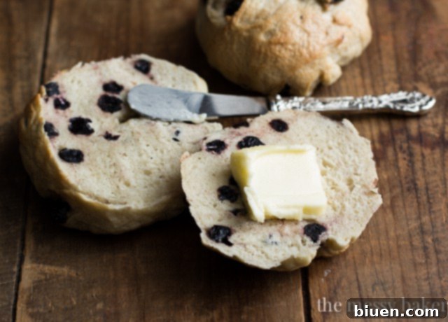 A toasted Honey Wheat Blueberry Bagel slathered with butter, ready to be eaten