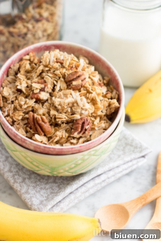 A bowl of chunky banana maple granola with milk and fresh banana slices