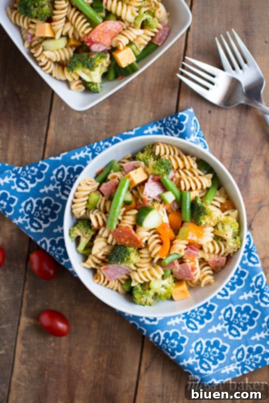 Colorful Summer Pasta Salad in a large glass bowl, garnished with herbs