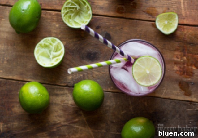 Sparkling Blackberry-Lime Gin Fizz 4 Blackberry Simple Syrup | Homemade blackberry simple syrup being strained through a fine-mesh sieve, showing its rich purple color.