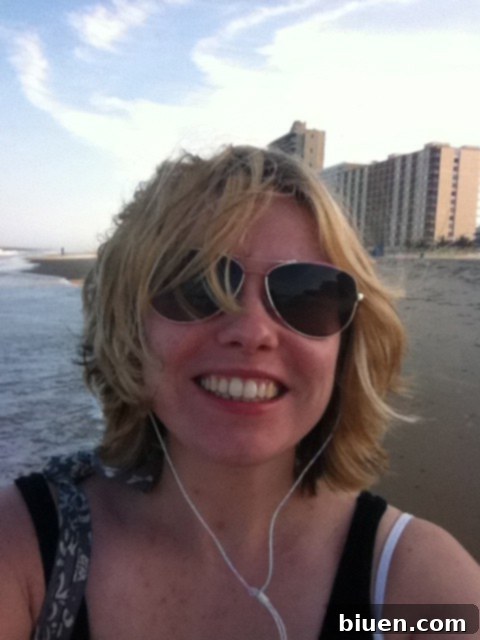 A woman's hands applying sunblock to her face, emphasizing sun protection and skincare at the beach for a safe summer experience.