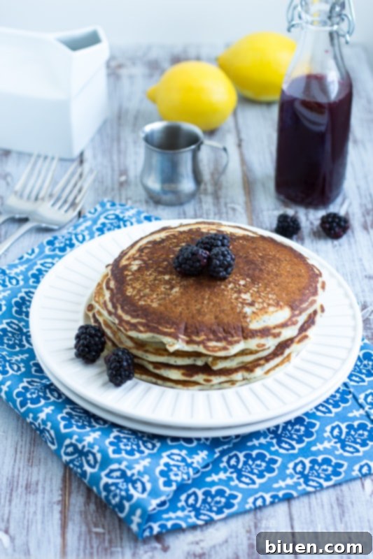 Fluffy Lemon Poppy Seed Pancakes stacked with fresh blackberries and lemon slices