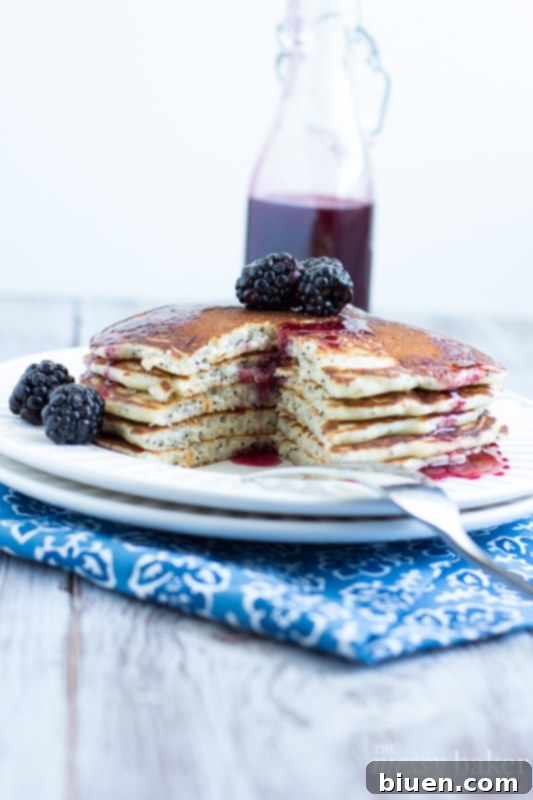 Close-up of Lemon Poppy Seed Pancakes drizzled with homemade blackberry maple syrup and fresh fruit