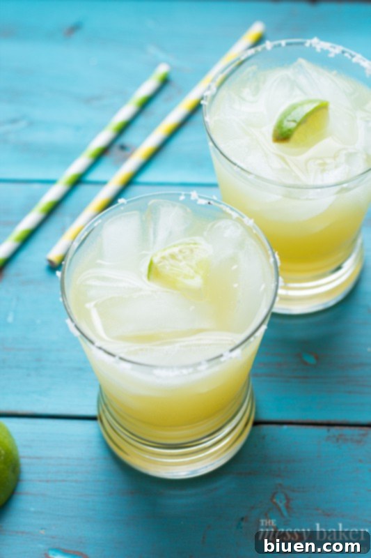 Pineapple Margarita pitcher being poured into a glass with ice