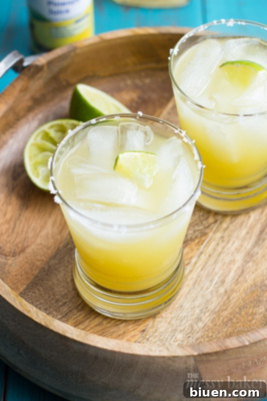 Finished Pineapple Margarita cocktail in a salted glass, garnished with lime and pineapple