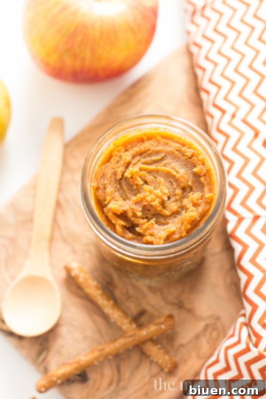 Homemade White Chocolate Pumpkin Almond Butter in a glass jar, adorned with autumn leaves, ready to be enjoyed with a spoon.