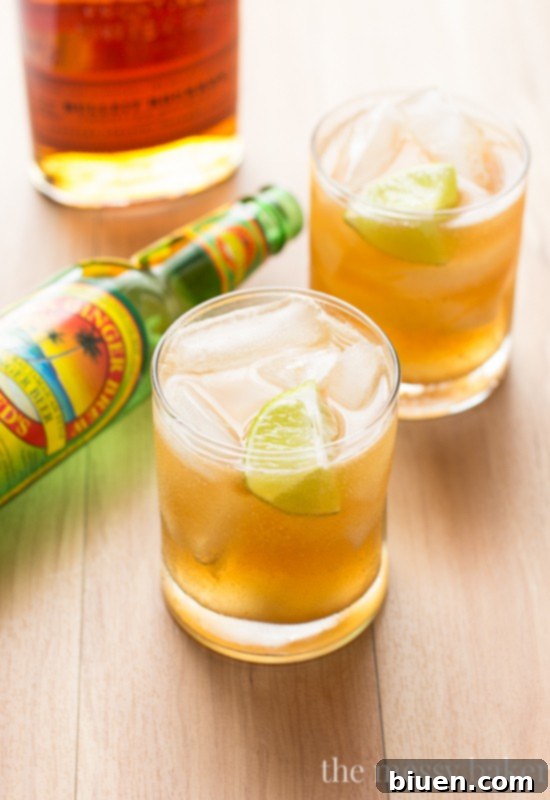 Apple Ginger Bourbon Cocktail in a elegant glass with a lime wedge, ready to be enjoyed, showcasing its rich autumn colors.