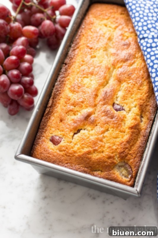 Sweet Grape Ricotta Pound Cake 2 Delicious Ricotta Pound Cake with Red Grapes and a light dusting of powdered sugar, presented beautifully on a cutting board, ready to be sliced.