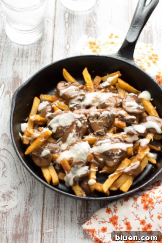 Gluten-Free Mushroom Swiss Poutine | A tantalizing dish of crispy fries, rich mushroom gravy, and gooey Swiss cheese sauce, served on a rustic board.