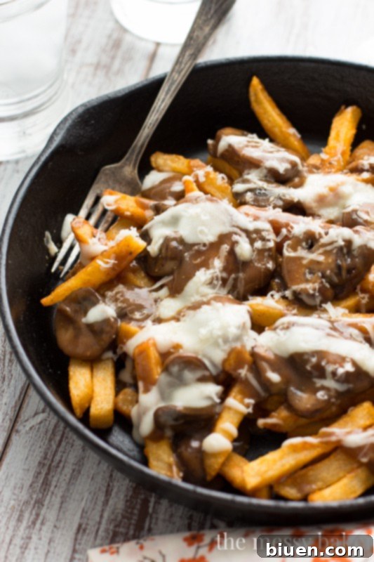 Gluten-Free Mushroom Swiss Poutine | A side view of the poutine, showing the layering of fries, gravy, and cheese sauce.