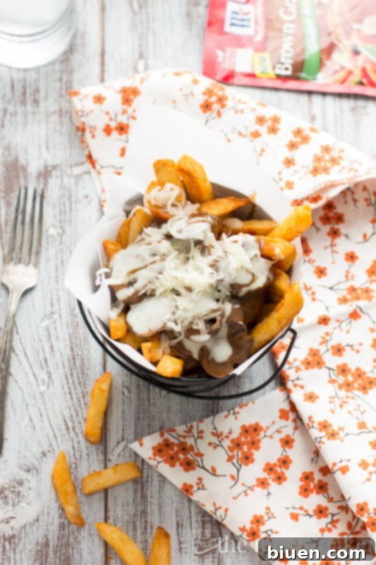 Gluten-Free Mushroom Swiss Poutine | A close-up of a fork digging into the poutine, highlighting the melty cheese and hearty gravy.