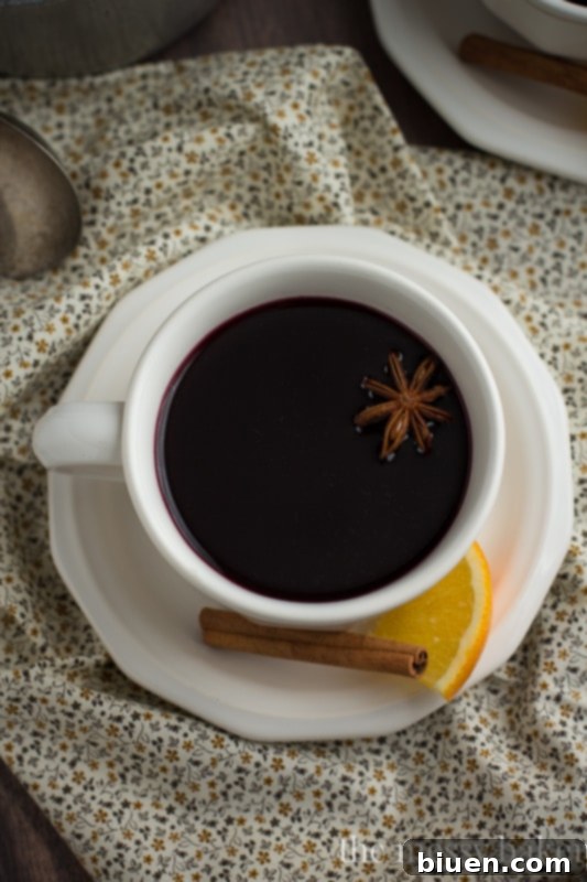 Ingredients for Pomegranate Mulled Wine laid out on a wooden surface, including a bottle of wine, pomegranates, and spices