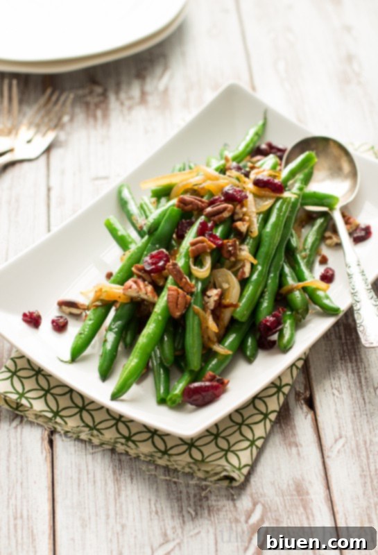 This easy side dish is perfect for Thanksgiving. Crisp green beans get tossed with caramelized onions, toasted pecans, and dried cranberries. | www.themessybakerblog.com