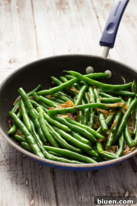This easy side dish is perfect for Thanksgiving. Crisp green beans get tossed with caramelized onions, toasted pecans, and dried cranberries. | www.themessybakerblog.com