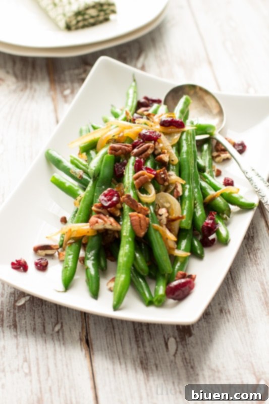 This easy side dish is perfect for Thanksgiving. Crisp green beans get tossed with caramelized onions, toasted pecans, and dried cranberries. | www.themessybakerblog.com