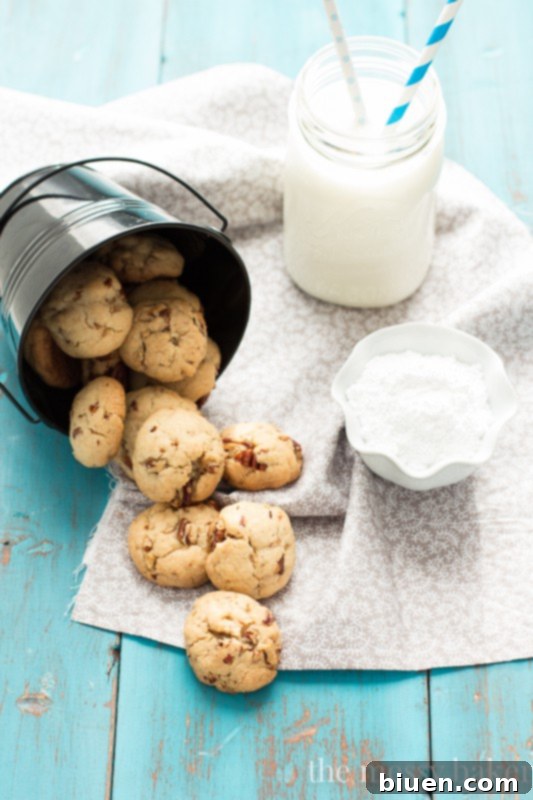 Grandmom's Pecan Sandies | Freshly baked Pecan Sandies, lightly golden, before their powdered sugar dusting, showing off the embedded pecan pieces.