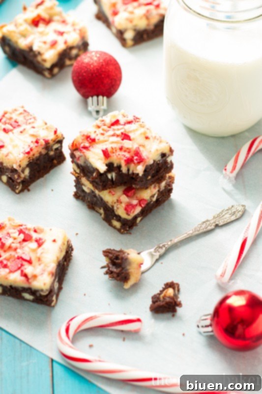 A top-down view of Peppermint Cheesecake Swirl Brownies cooling on a wire rack, with a festive background