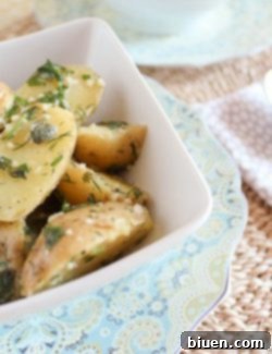 A finished serving of buttery herbed potatoes in a small bowl, garnished with herbs.