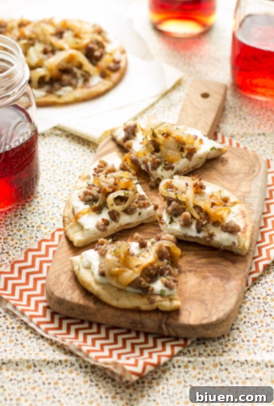 Close-up of Sausage & Caramelized Onion Pita Pizza, showcasing the rich toppings and golden-brown pita.