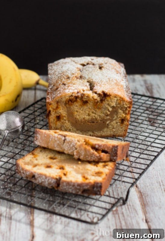 A beautifully baked loaf of Banana Bread with Cookie Butter Cheesecake Swirl, showing the golden crust