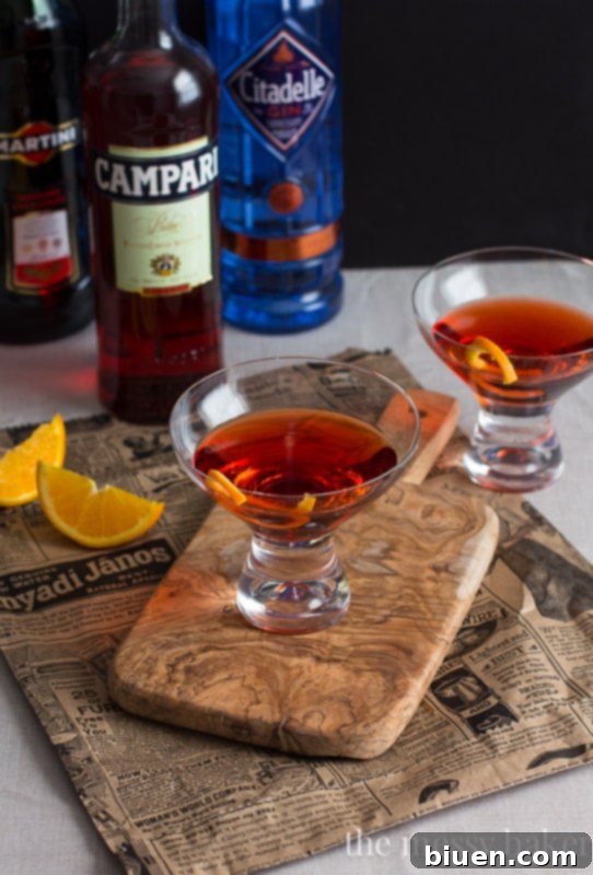 Classic Negroni Cocktail with a vibrant red hue in a clear glass.