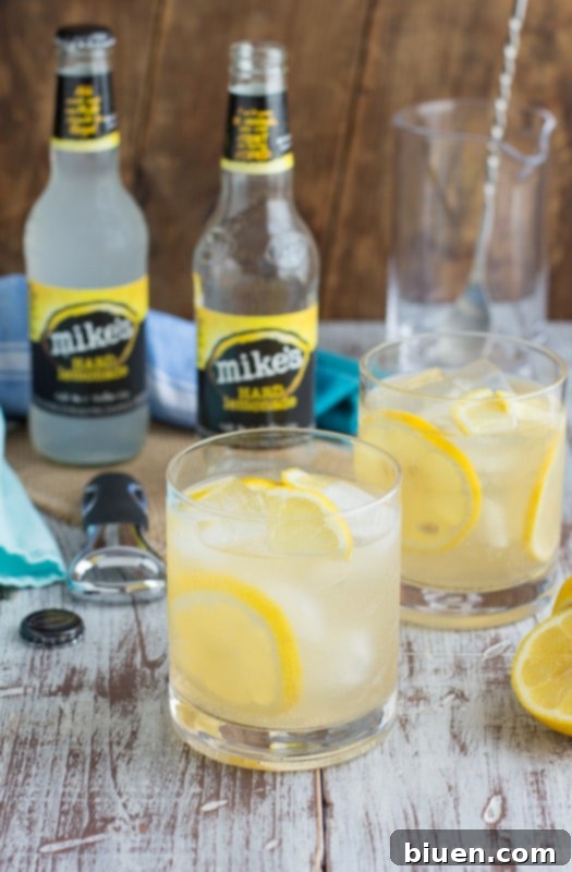 Thirsty Thursday Vanilla Bourbon Quencher 5 Several glasses of Vanilla Bourbon Lemonade, garnished with lemon slices, are arranged on a wooden serving tray for a summer gathering.