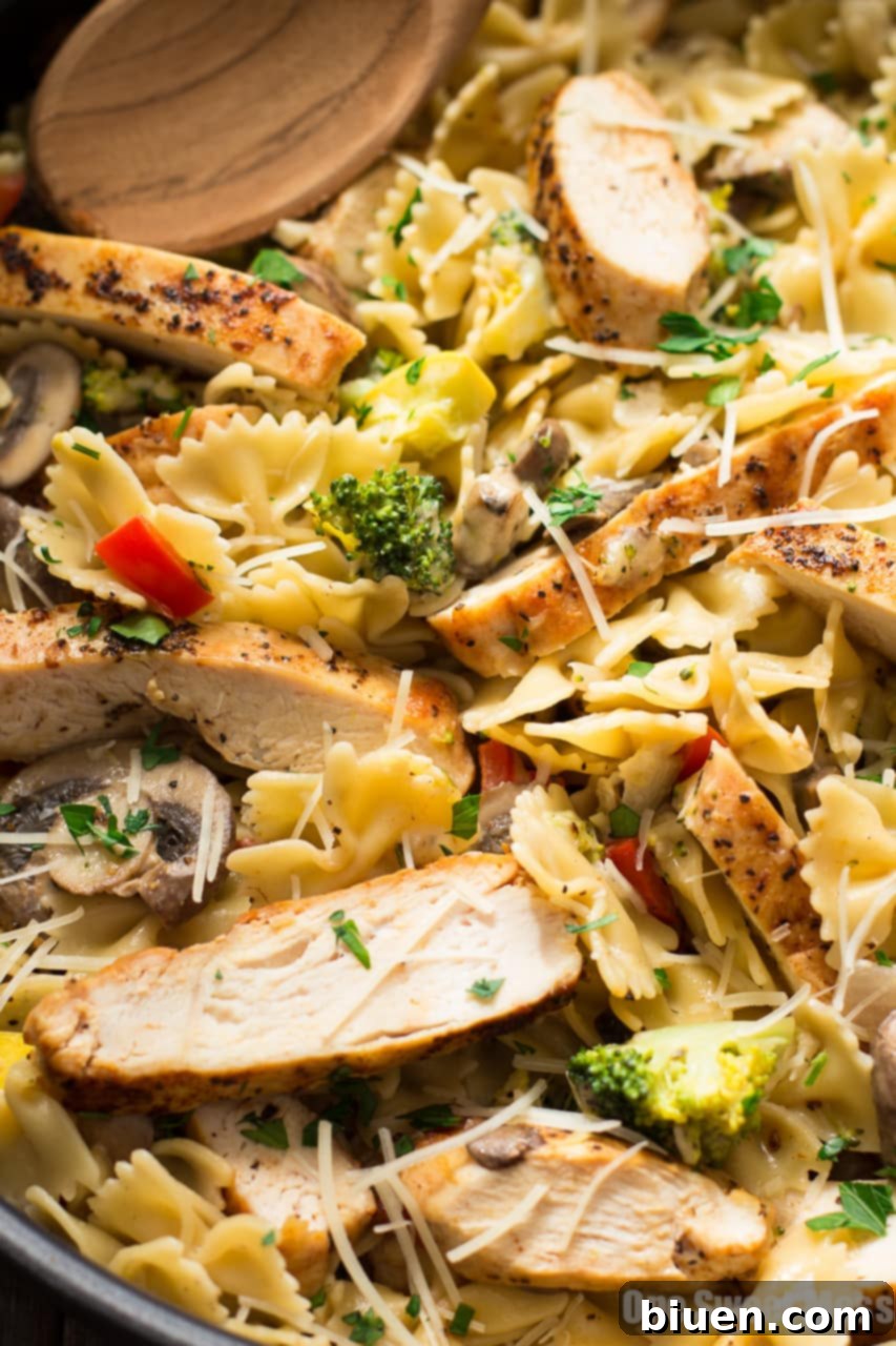 Chicken Alfredo Primavera in a serving bowl: A large bowl overflowing with Chicken Alfredo Primavera, garnished with fresh herbs, demonstrating its generous portion size and readiness for family serving.