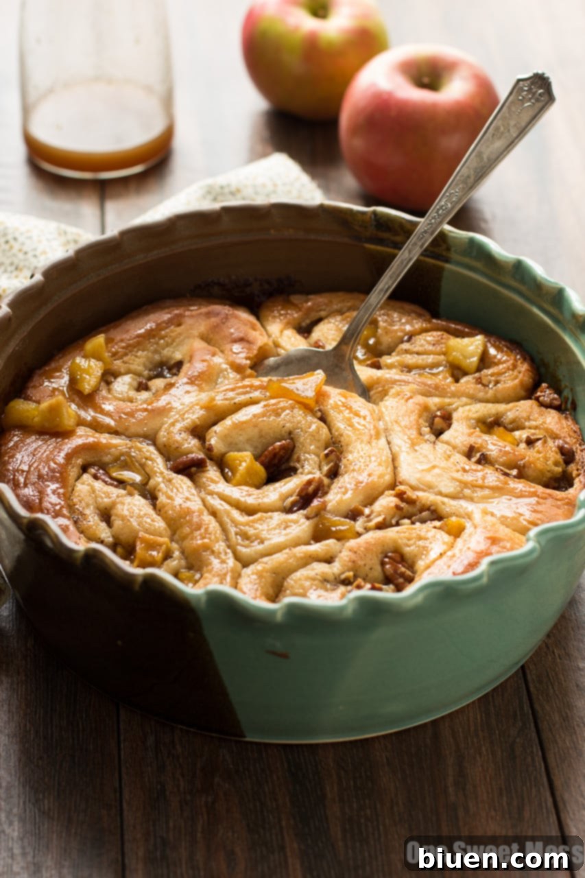 A baking dish full of warm caramel apple cinnamon rolls with caramel drizzle